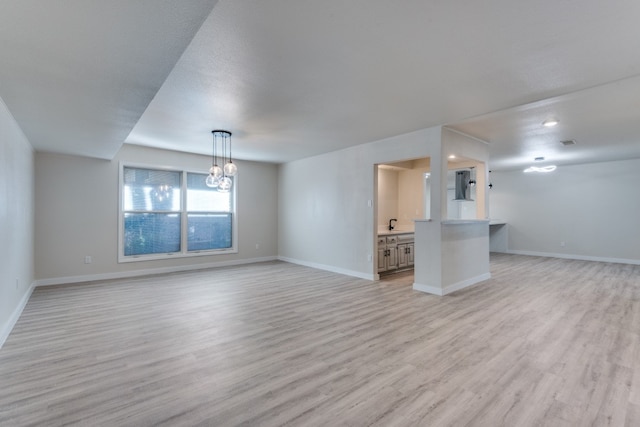 unfurnished living room featuring light hardwood / wood-style floors and an inviting chandelier