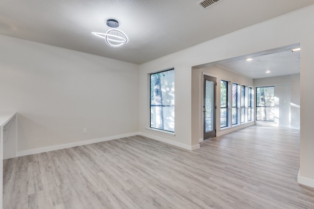 spare room with a textured ceiling and light hardwood / wood-style floors