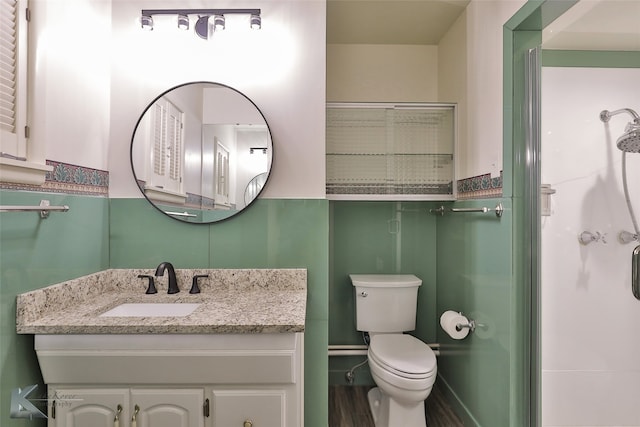 bathroom featuring hardwood / wood-style floors, vanity, toilet, and a shower