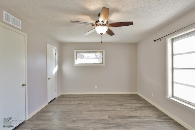 unfurnished room with ceiling fan, a textured ceiling, and light wood-type flooring