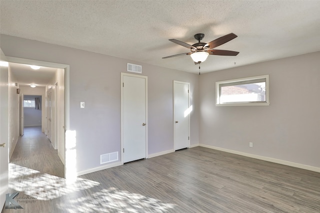 unfurnished bedroom featuring wood-type flooring, a textured ceiling, and ceiling fan