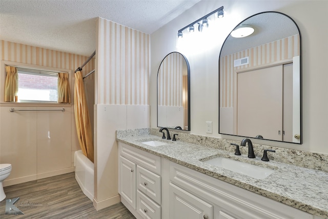 full bathroom featuring vanity, shower / bath combination with curtain, toilet, a textured ceiling, and wood-type flooring