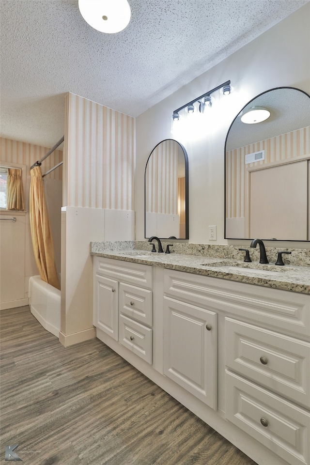 bathroom with vanity, hardwood / wood-style floors, a textured ceiling, and shower / bath combo with shower curtain