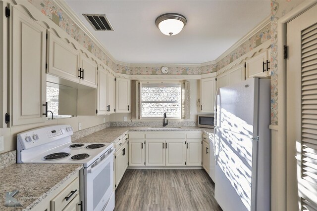 kitchen featuring white cabinetry, sink, light hardwood / wood-style flooring, white appliances, and ornamental molding