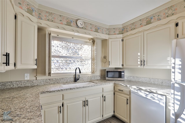 kitchen featuring white cabinetry, light stone countertops, white appliances, and sink