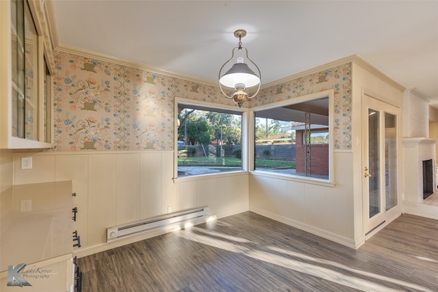 unfurnished dining area featuring dark wood-type flooring, crown molding, and a baseboard heating unit