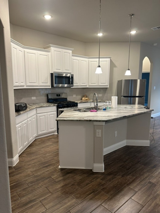 kitchen featuring appliances with stainless steel finishes, white cabinetry, a kitchen island with sink, and dark wood-type flooring