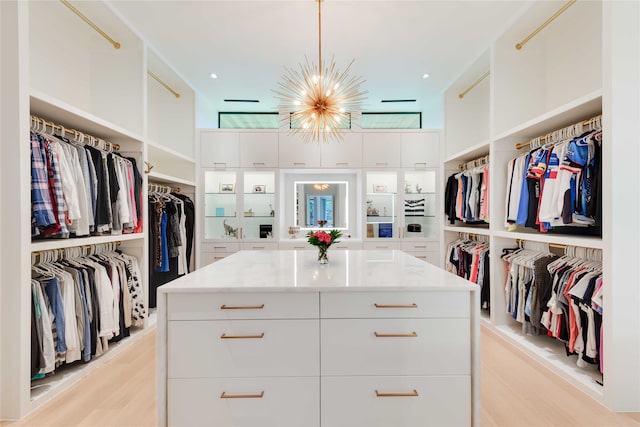 spacious closet featuring light hardwood / wood-style flooring and a notable chandelier