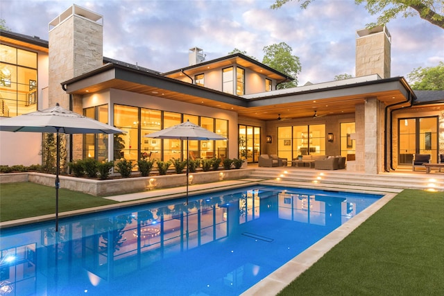 pool at dusk featuring outdoor lounge area and a patio