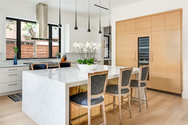 kitchen with light hardwood / wood-style floors, decorative light fixtures, a kitchen island, and white cabinetry