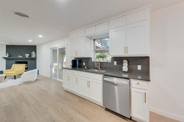 kitchen featuring white cabinetry, dishwasher, sink, a fireplace, and light wood-type flooring