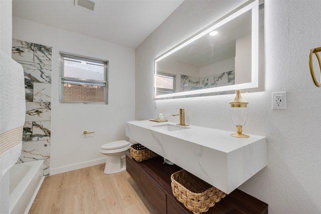 full bathroom with vanity, hardwood / wood-style flooring, toilet, and tiled shower / bath