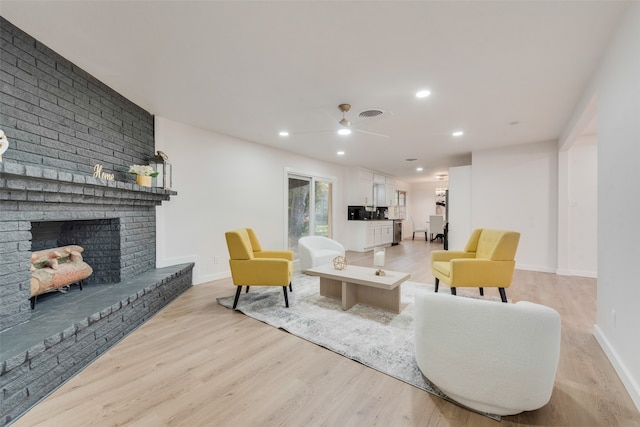 living room with a fireplace, light hardwood / wood-style floors, and ceiling fan