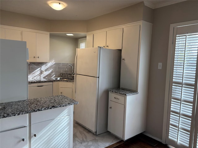 kitchen featuring white cabinets, decorative backsplash, white appliances, and dark stone counters