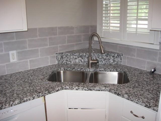 kitchen with white cabinets, decorative backsplash, stone counters, and sink