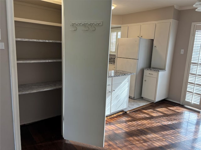 kitchen featuring light stone countertops, white cabinets, light wood-type flooring, and white refrigerator