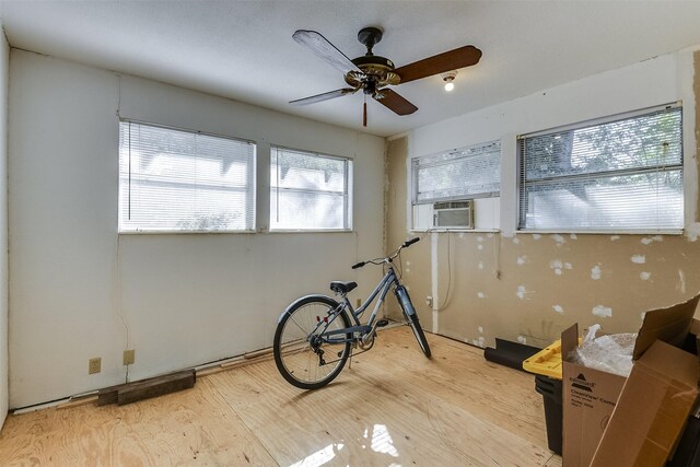 misc room with light hardwood / wood-style flooring, cooling unit, and ceiling fan