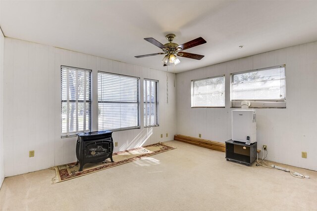 misc room featuring carpet floors, a wood stove, plenty of natural light, and ceiling fan