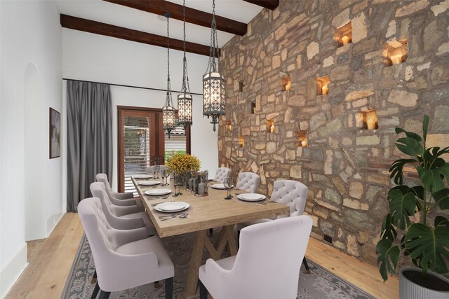 unfurnished dining area featuring beamed ceiling, french doors, and light hardwood / wood-style floors