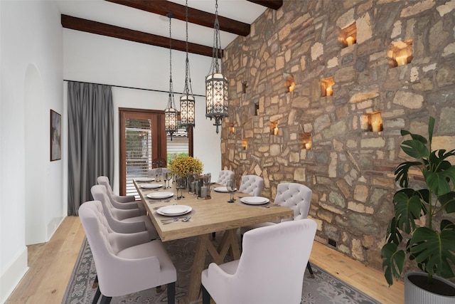 dining area featuring a towering ceiling, wood finished floors, and beam ceiling