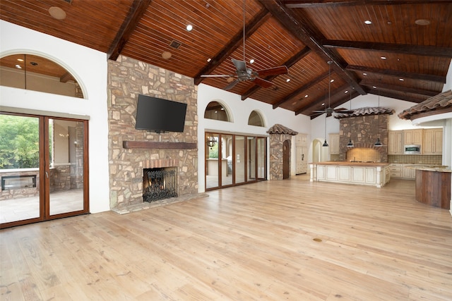 unfurnished living room with high vaulted ceiling, a stone fireplace, ceiling fan, light wood-type flooring, and wood ceiling