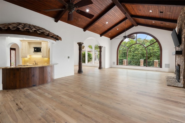 unfurnished living room with arched walkways, light wood finished floors, wood ceiling, ceiling fan, and high vaulted ceiling