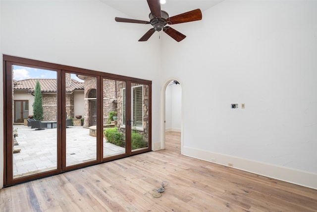 spare room featuring ceiling fan, light hardwood / wood-style floors, and a towering ceiling