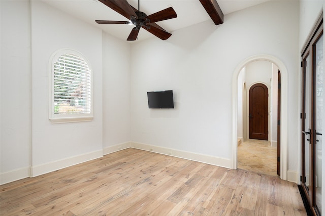 spare room with beamed ceiling, light hardwood / wood-style floors, and ceiling fan