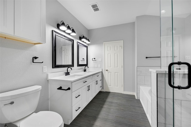 bathroom with hardwood / wood-style flooring, vanity, toilet, and a tub