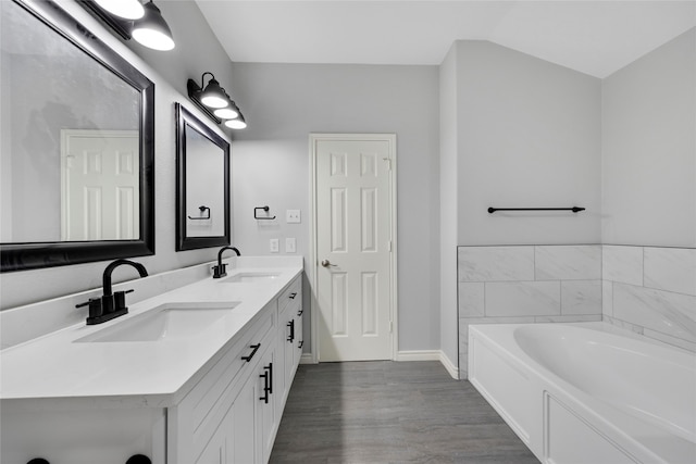 bathroom with vanity, a tub to relax in, and wood-type flooring