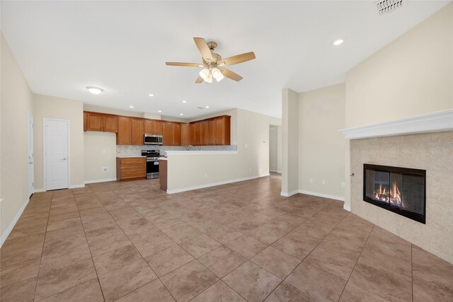 kitchen featuring a tile fireplace, ceiling fan, appliances with stainless steel finishes, backsplash, and light tile patterned flooring