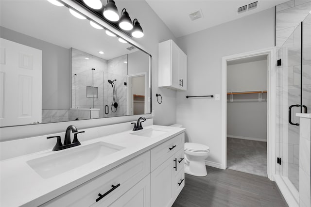 bathroom with toilet, vanity, and a shower with shower door