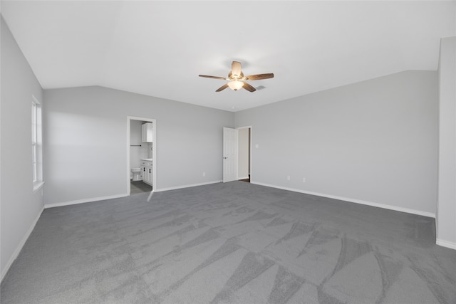 unfurnished bedroom featuring ceiling fan, lofted ceiling, connected bathroom, and dark carpet