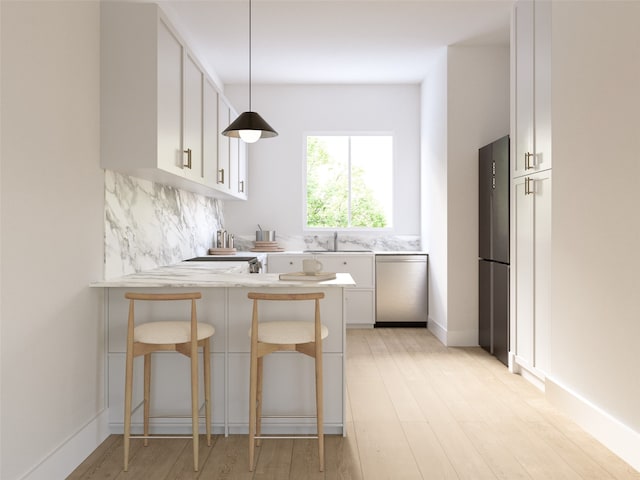 kitchen with pendant lighting, a kitchen bar, white cabinetry, and appliances with stainless steel finishes