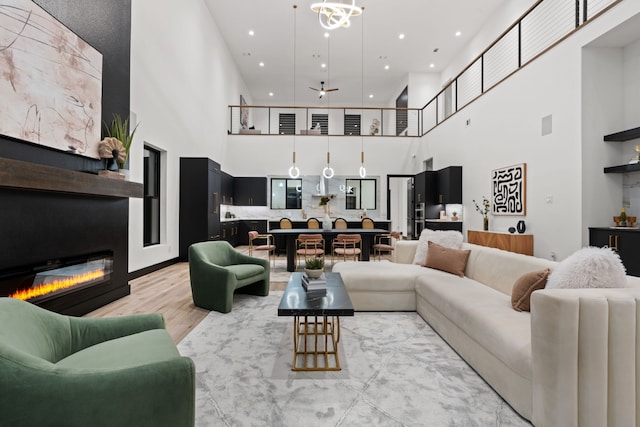 living room featuring a notable chandelier, a high ceiling, and light wood-type flooring