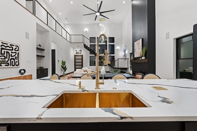 kitchen featuring a high ceiling, light stone counters, and sink