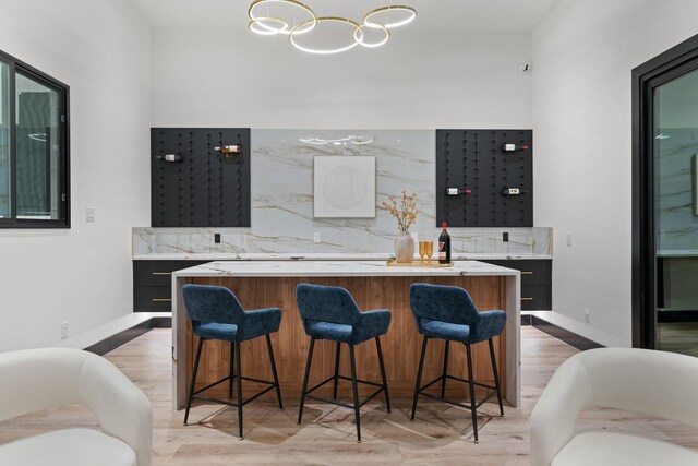 kitchen with a kitchen bar, light hardwood / wood-style floors, a kitchen island, and tasteful backsplash