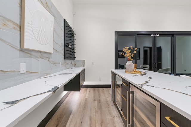 kitchen featuring wine cooler, light stone counters, and light hardwood / wood-style flooring