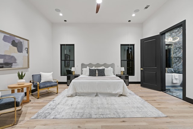 bedroom featuring ceiling fan, light hardwood / wood-style floors, and a towering ceiling