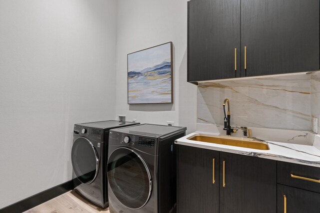 laundry room with washer and dryer, cabinets, sink, and light hardwood / wood-style flooring