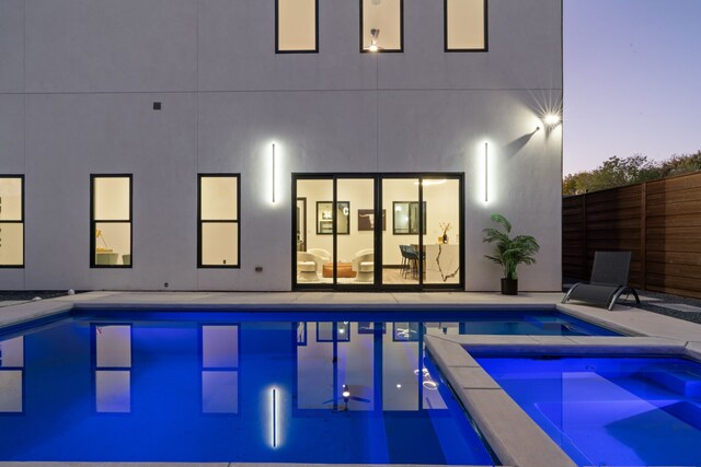 pool at dusk featuring an in ground hot tub