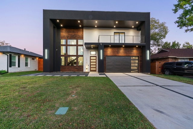 contemporary home with a yard, a balcony, and a garage