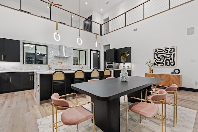 kitchen featuring a breakfast bar area, a center island, a towering ceiling, and light wood-type flooring