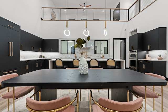 dining area featuring a high ceiling, light hardwood / wood-style floors, and ceiling fan