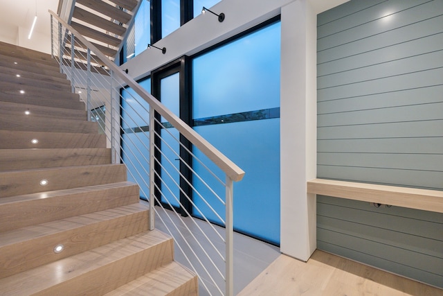 stairs with wood walls and hardwood / wood-style flooring