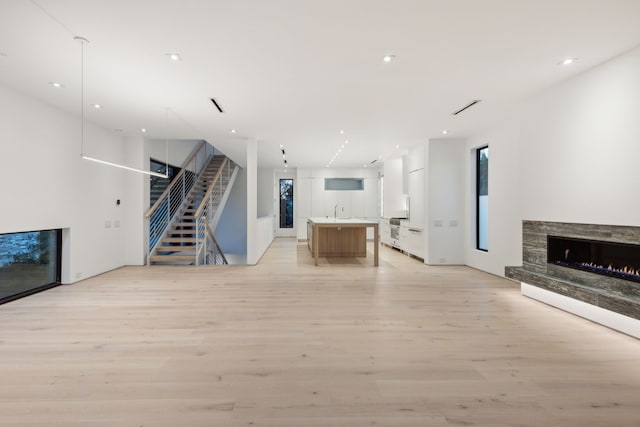 unfurnished living room featuring light hardwood / wood-style floors, sink, and a fireplace