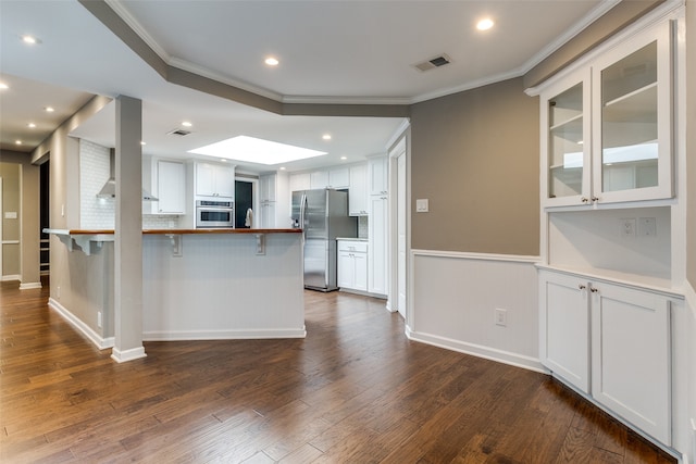 kitchen with dark hardwood / wood-style floors, white cabinetry, kitchen peninsula, and appliances with stainless steel finishes