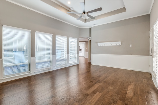 empty room with a raised ceiling, ceiling fan, dark hardwood / wood-style floors, and ornamental molding