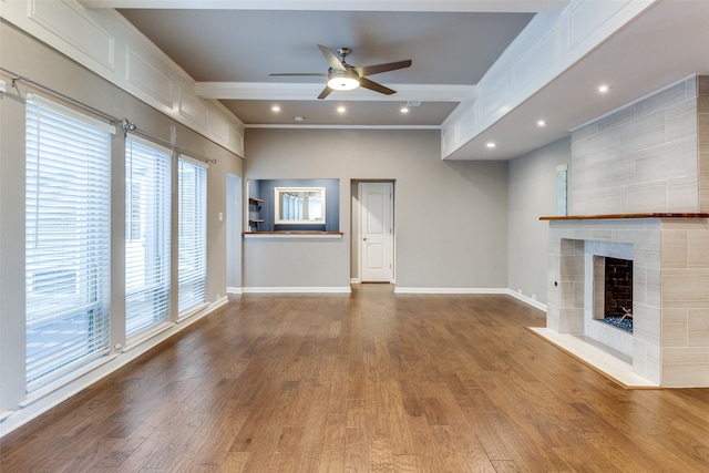 unfurnished living room featuring ceiling fan, light hardwood / wood-style floors, ornamental molding, and a tiled fireplace