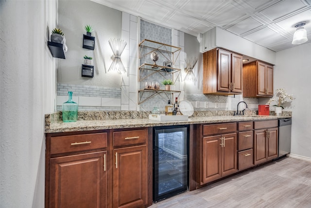 bar featuring backsplash, stainless steel dishwasher, beverage cooler, sink, and light hardwood / wood-style floors